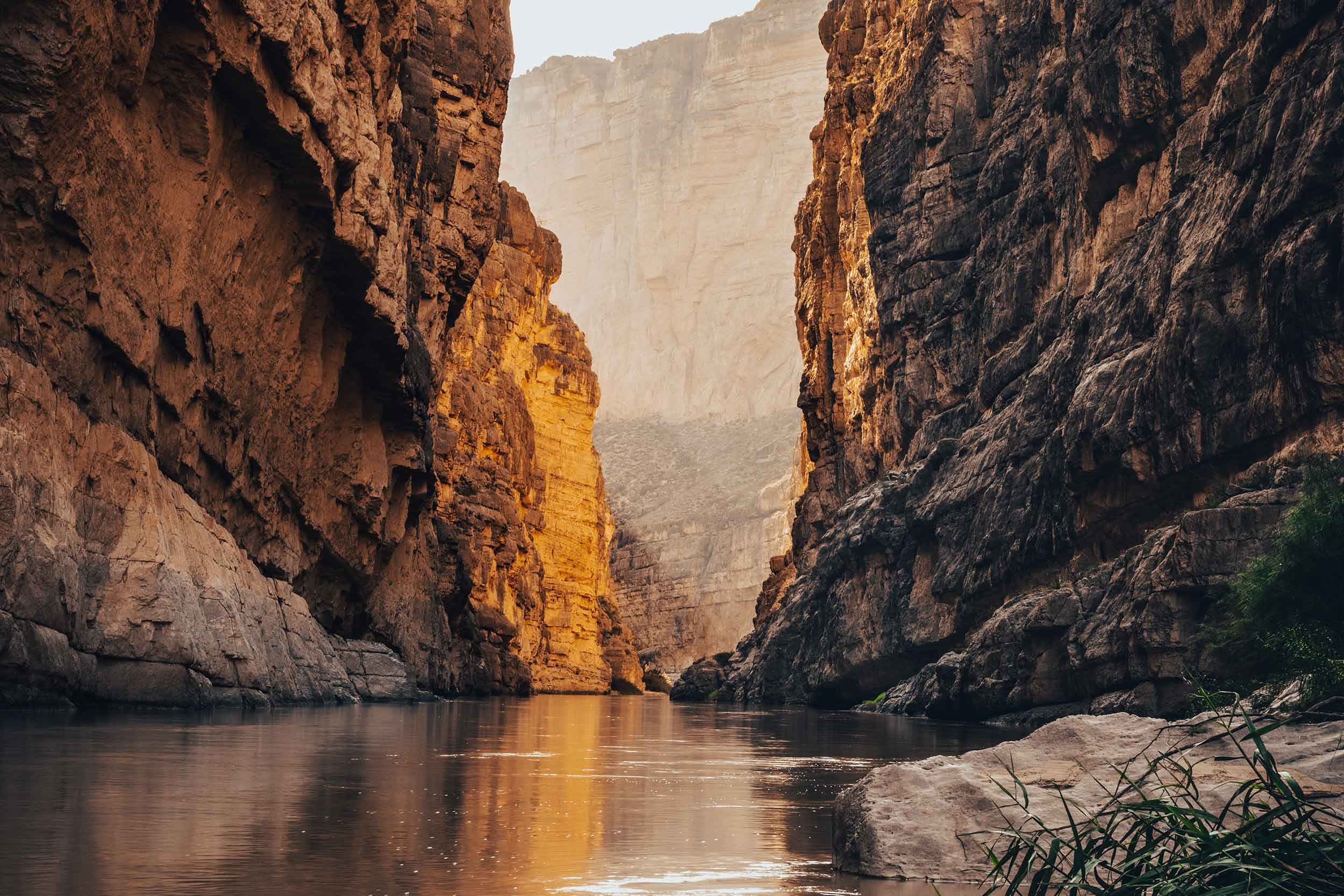 Sunlit canyon walls narrowing over dark water in Santa Elena