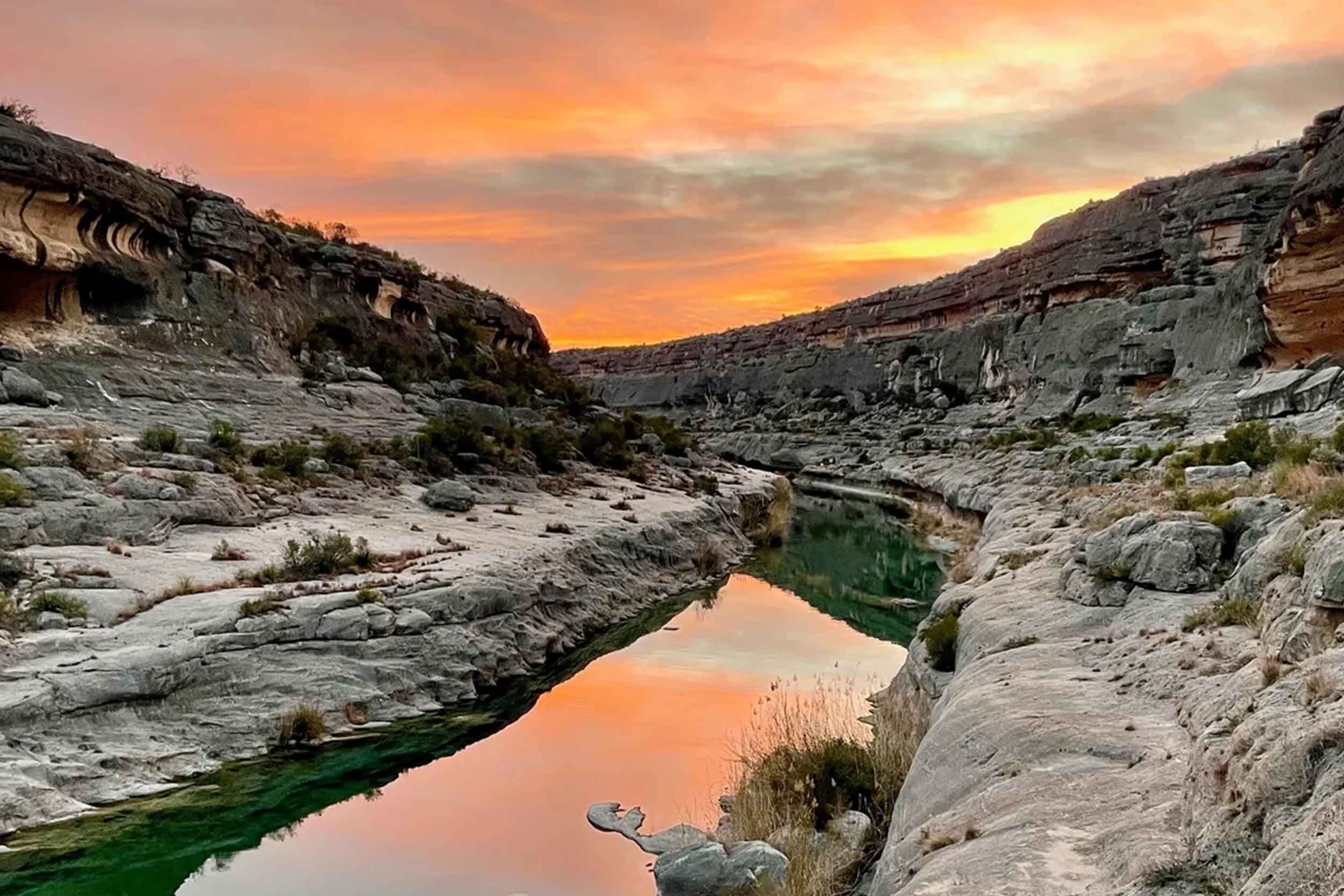 Sunset over limestone benches and a still green pool