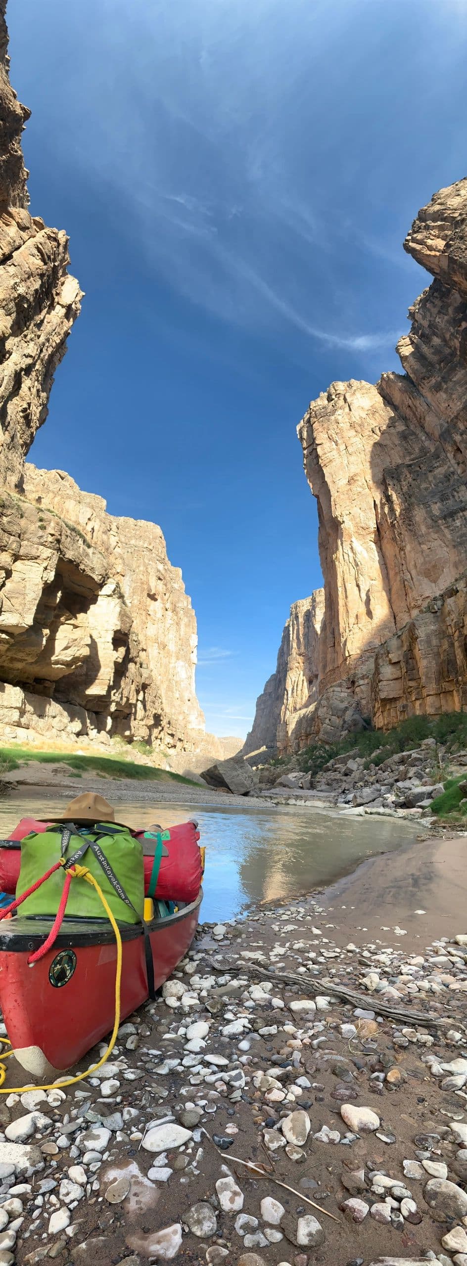 Loaded red canoe on cobbles below a canyon narrows